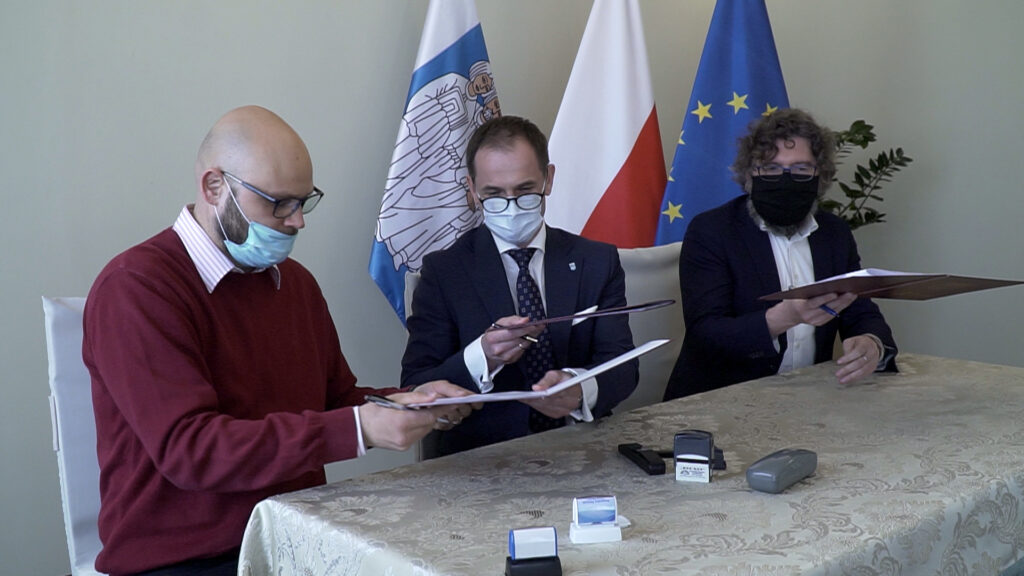 Zdjęcie przedstawia trzech mężczyzn podpisujących porozumienie.